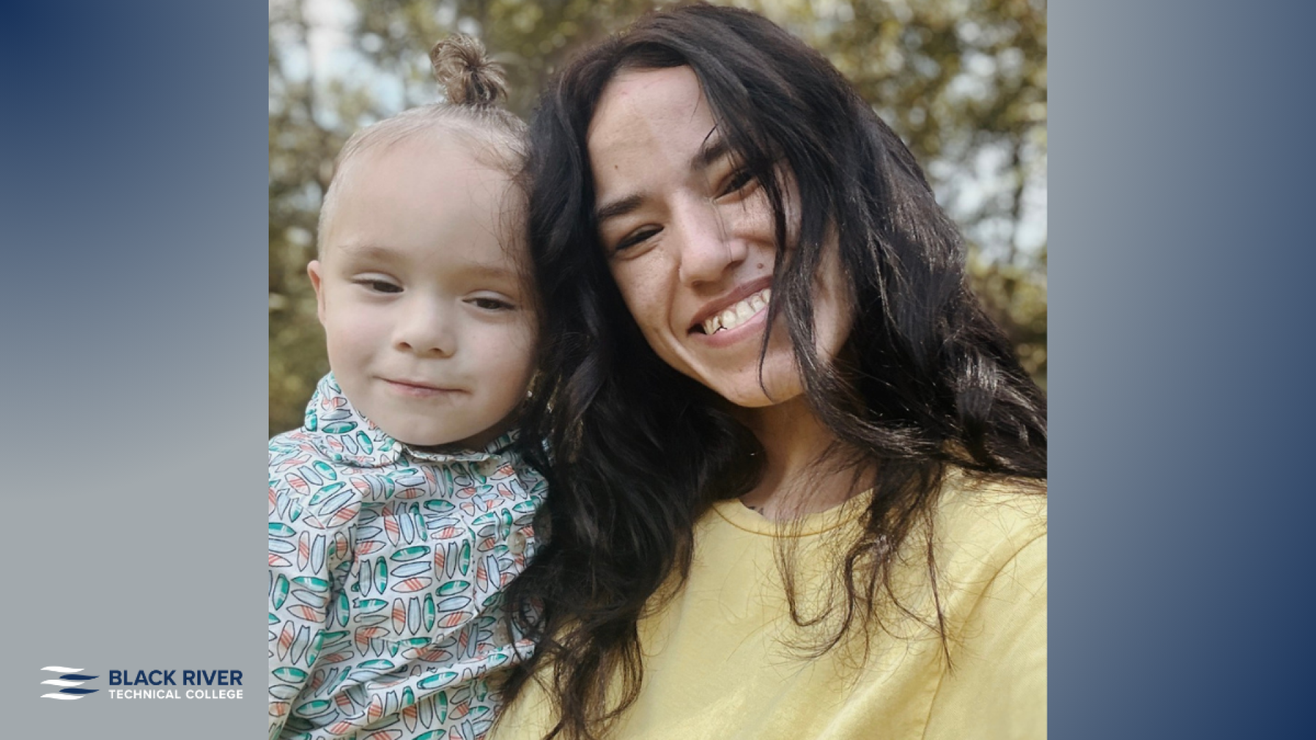 A woman with long dark hair in a yellow top smiles closely with a young child in a patterned outfit, outdoors among trees, with Black River Technical College branding.